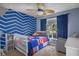 Bright bedroom featuring a blue accent wall, ceiling fan and a cozy white crib with Spiderman bedding at 1003 Hart Branch Dr, Oviedo, FL 32765