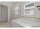 Bright bathroom features a luxurious soaking tub and a glass enclosed shower with tiled accents at 1151 Wildmeadow Run, Winter Park, FL 32792
