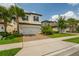 Charming two-story home featuring a well-manicured lawn, palm trees, and a two-car garage at 1151 Wildmeadow Run, Winter Park, FL 32792