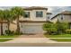 Charming two-story home with an attached two-car garage, brick driveway, and lush tropical landscaping at 1151 Wildmeadow Run, Winter Park, FL 32792