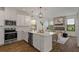 Stylish open-concept kitchen with white cabinets, modern appliances, and seamless flow to the living room at 1151 Wildmeadow Run, Winter Park, FL 32792