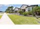 Well-manicured lawn and garden beds frame this stylish home with a brick driveway and lush palm trees at 1265 Zeek Ridge St, Clermont, FL 34715