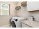 Functional laundry room features modern appliances, ample counter space, storage, and a bright window at 1265 Zeek Ridge St, Clermont, FL 34715
