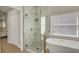 Bright bathroom showcasing a glass shower, a modern soaking tub, and elegant gold fixtures at 13430 Early Frost Cir, Orlando, FL 32828