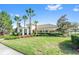 Exterior shot of a clubhouse with a manicured lawn, landscaping, and palm trees at 13430 Early Frost Cir, Orlando, FL 32828