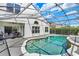 Screened-in pool and patio area, with an outdoor kitchen, lush landscaping and blue skies at 13430 Early Frost Cir, Orlando, FL 32828