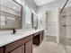 Bathroom with double sinks, framed mirrors, quartz countertops, and walk-in closet at 13662 Behring Ave, Orlando, FL 32827