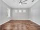 Empty bedroom showcasing wood floors, ceiling fan, neutral walls, and bright, shuttered windows at 13662 Behring Ave, Orlando, FL 32827