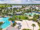 Aerial view of community amenities including pools, a beach volleyball court, and lush landscaping by a serene lake at 13662 Behring Ave, Orlando, FL 32827