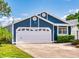 Two car garage with a white garage door and a well-manicured lawn with hedges and a tree at 148 Meadow Blvd, Sanford, FL 32771