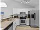 Bright kitchen featuring stainless steel appliances, granite countertops, and sleek white cabinetry at 1527 Braewick St, Winter Springs, FL 32708