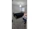 Cozy bedroom with carpet, a bed with black bedding, a side table, and a window at 1540 Fleur Dr, Davenport, FL 33837