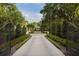 Long private driveway leading to a luxurious estate, framed by manicured landscaping and a decorative gate at 1640 E Adams Dr, Maitland, FL 32751