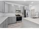 Modern kitchen featuring gray cabinets, stainless steel appliances, and a large island with quartz countertops at 16927 Sw 25Th Terrace Rd, Ocala, FL 34473