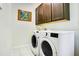Efficient laundry area with side-by-side washer and dryer plus upper cabinet storage at 18108 Bellezza Dr, Orlando, FL 32820