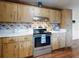 Kitchen showcasing wooden cabinets, oven with range hood, and cherry themed wallpaper at 1872 N Akron Dr, Deltona, FL 32738