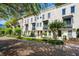 Charming townhome showcases a white facade, manicured landscaping, and a welcoming brick-paved street at 220 S Summerlin Ave, Orlando, FL 32801