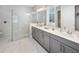 Elegant bathroom featuring a glass-enclosed shower, dual sinks, and sleek gray cabinetry at 2332 Salty Winds Way, Kissimmee, FL 34747