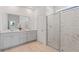 Modern bathroom with a double sink vanity, a large mirror, and a glass-enclosed shower with marble-style tiling at 2770 Sweet Acacia Dr, Clermont, FL 34711