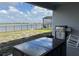 Covered back patio featuring a stainless steel grill, dining table, and view of the lake at 2926 Wordsmith Rd, Kissimmee, FL 34746