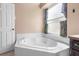 Bright bathroom with a large soaking tub under a window and a white tiled surround at 3137 Timucua Cir, Orlando, FL 32837