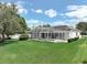 Expansive backyard showcasing white home, well-manicured lawn, and screened-in pool area at 3534 Woodley Park Pl, Oviedo, FL 32765