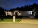 Well-lit home at night with a manicured lawn and a covered car parked in the driveway at 3534 Woodley Park Pl, Oviedo, FL 32765