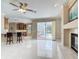 This open concept living room features tile flooring, a fireplace, and barstool seating at the kitchen counter at 3534 Woodley Park Pl, Oviedo, FL 32765