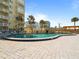 Community pool surrounded by palm trees and pavers, with views of the building at 3606 S Peninsula Dr # 707, Port Orange, FL 32127