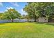 Expansive backyard featuring green grass, mature trees, a shed, and a privacy fence at 5162 Tellson Pl, Orlando, FL 32812