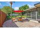 A patio featuring brick pavers and outdoor seating with a red umbrella in a landscaped backyard at 5162 Tellson Pl, Orlando, FL 32812