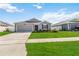 Charming single-story home with a well-manicured lawn, attached garage, and red accent shutters at 5347 Travertine St, Mount Dora, FL 32757