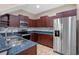 Well-appointed kitchen with stainless steel appliances, granite countertops, and dark wood cabinets at 8031 Enchantment Dr # Ge, Windermere, FL 34786