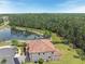 Aerial view of a home with a tiled roof, lush green backyard, and a picturesque lake nearby at 8478 Elba Isle Ct, Windermere, FL 34786