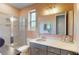 This bathroom has a tile shower with glass enclosure, vanity, grey cabinets, and a decorative sink at 8478 Elba Isle Ct, Windermere, FL 34786