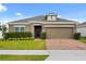 Charming single-story home featuring a well-maintained lawn, neat landscaping, and a brick-paved driveway at 849 Avenal Ln, Davenport, FL 33837