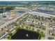 An aerial view of a townhome community featuring a pond with fountain, green spaces, and nearby highway access at 9009 Savannah Julip Ln, Orlando, FL 32832