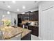 Well-lit kitchen featuring granite countertops, dark cabinetry, stainless steel appliances and modern fixtures at 9009 Savannah Julip Ln, Orlando, FL 32832