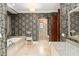 A luxurious bathroom features elegant wallpaper, granite counters, and a stand-alone bathtub at 9730 Lounsberry Cir, Golden Oak, FL 32836