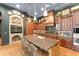 Kitchen with a large granite island, brick fireplace, and wooden cabinets at 9730 Lounsberry Cir, Golden Oak, FL 32836