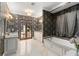 Bathroom featuring patterned wallpaper, double sinks, a soaking tub, and pool access at 9730 Lounsberry Cir, Golden Oak, FL 32836