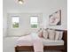 Bright bedroom with two windows, light walls, soft carpet, and a cozy bed with decorative pillows at 10139 Austrina Oak Loop, Winter Garden, FL 34787