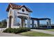Stone entrance to Watermark community with tiled roof, lake views, and decorative lighting at 10139 Austrina Oak Loop, Winter Garden, FL 34787