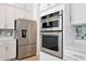 Stainless steel refrigerator and built-in ovens in a modern white kitchen at 10139 Austrina Oak Loop, Winter Garden, FL 34787