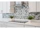 Close up of modern kitchen with white cabinets and stainless steel range hood and backsplash at 10139 Austrina Oak Loop, Winter Garden, FL 34787