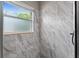 Shower with marble-patterned walls, a window, and sleek fixtures at 1130 Hardy Ave, Orlando, FL 32803