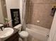 Bathroom features a tiled shower and tub combo, tiled floors, a single sink, and a decorative wall hanging at 119 Stewart Lake Loop, Groveland, FL 34736