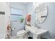 Bathroom featuring a white pedestal sink, round mirror and window providing natural light at 1421 N Hampton Ave, Orlando, FL 32803