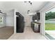 Modern kitchen with dark cabinets, tile flooring, and stainless steel appliances, adjacent to living room at 14878 Se 32Nd Ter, Summerfield, FL 34491