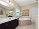 Bright bathroom with a large soaking tub, double vanity, and tile flooring at 15242 Heron Hideaway Cir, Winter Garden, FL 34787